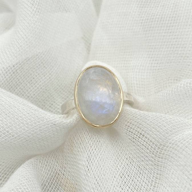 Moonstone oval ring with gold bezel walls and sterling silver band