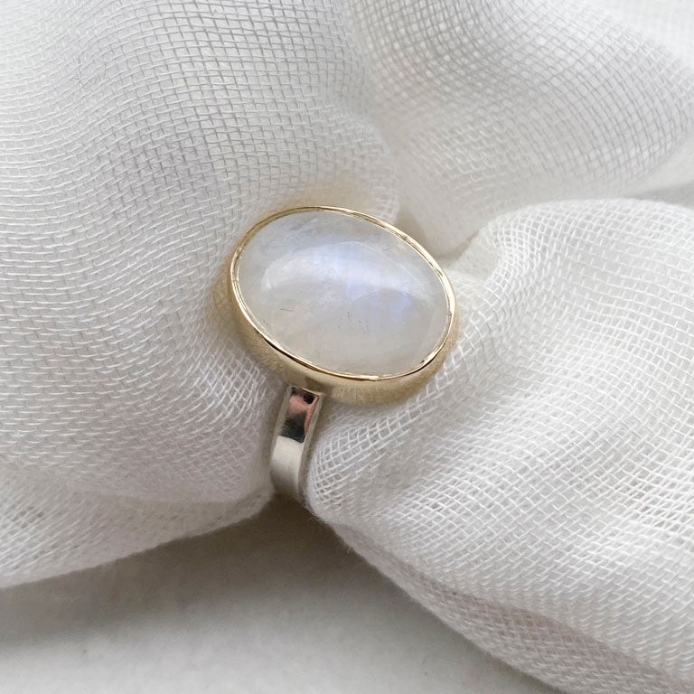 Moonstone oval ring with gold bezel walls and sterling silver band