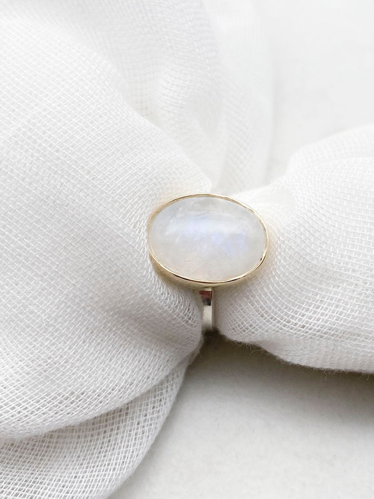 Moonstone oval ring with gold bezel walls and sterling silver band