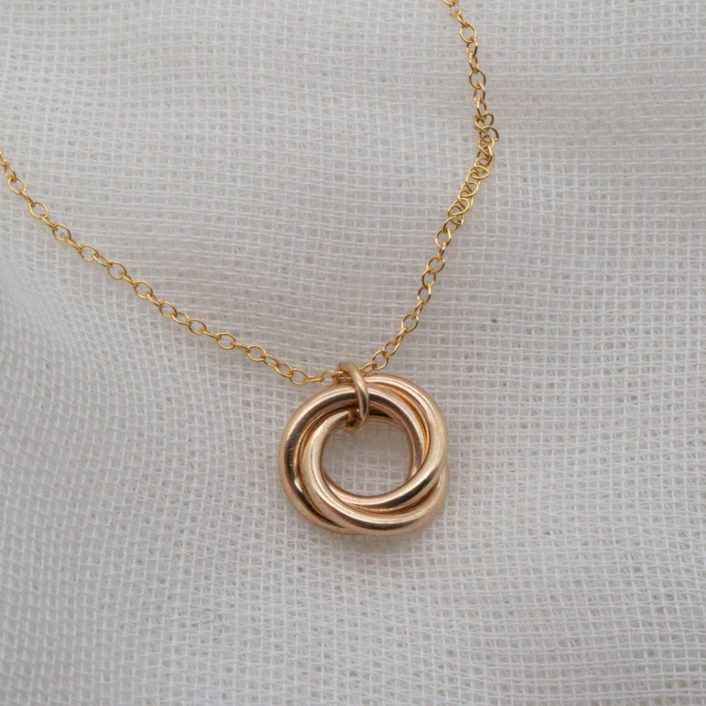 rolled gold 3 ringed pendant necklace on white background
