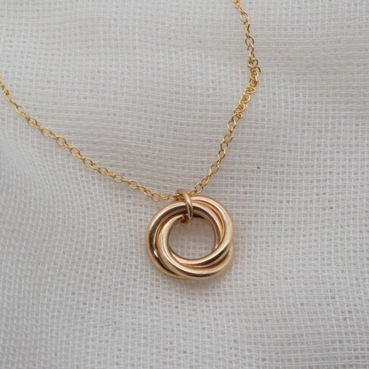 rolled gold 3 ringed pendant necklace on white background
